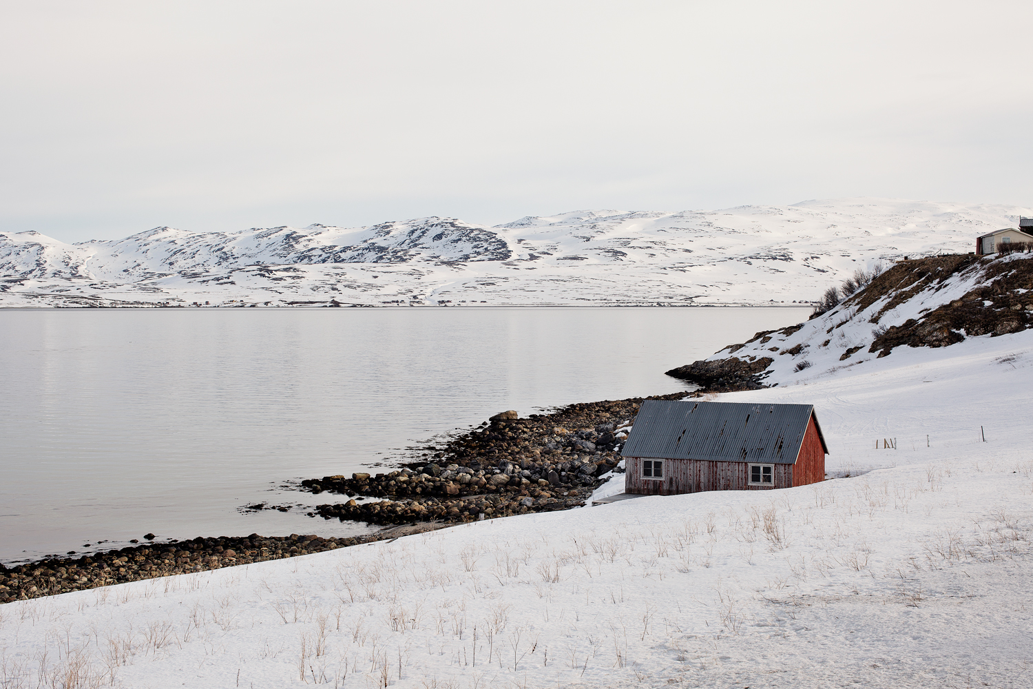 en naust foran en blikkstille fjord i Nord-Norge